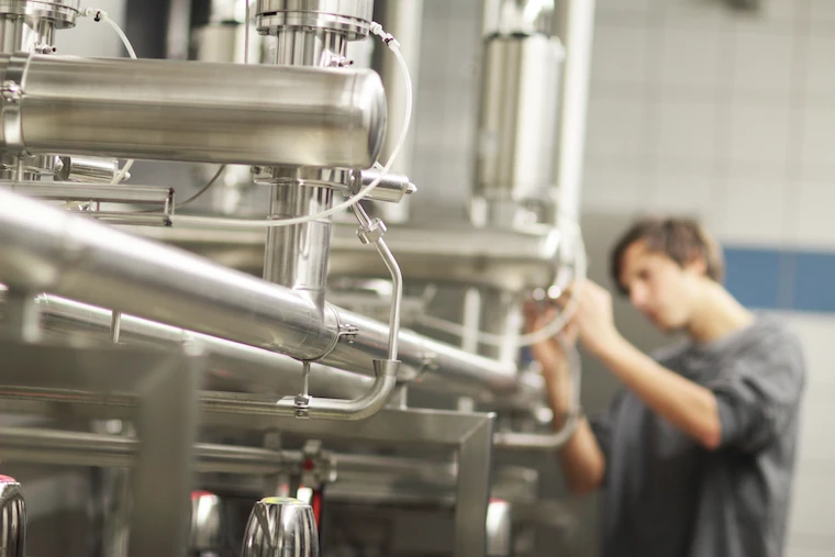 Worker checking stainless steel brewery equipment