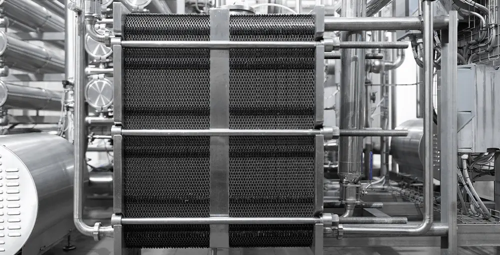 Side view of a large plate and frame heat exchanger connected to process piping